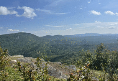Cliffside view from Holt’s Ledge trail in Lyme, New Hampshire, with mountain peaks visible in the distance.